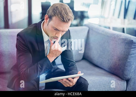 Thoughtful businessman looking at digital tablet Stock Photo