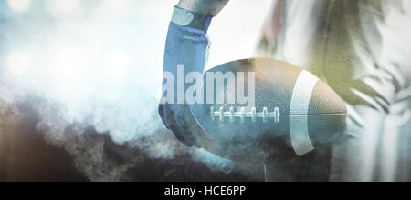 Composite image of cropped image of sportsman holding american football ball ball Stock Photo