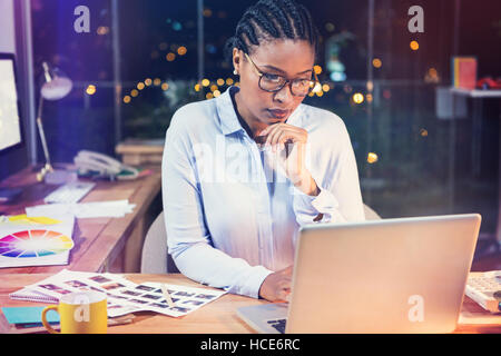 Thoughtful businesswoman working on laptop Stock Photo