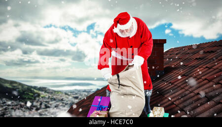 Composite image of santa claus filling gift boxes in sack Stock Photo