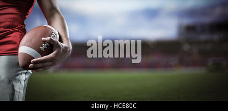 Composite image of cropped image of sportsman holding american football Stock Photo