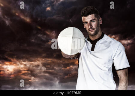 Composite image of portrait of rugby player holding the ball with one hand Stock Photo