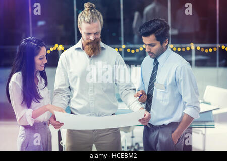 Businesswoman and businessmen discussing over blueprint Stock Photo