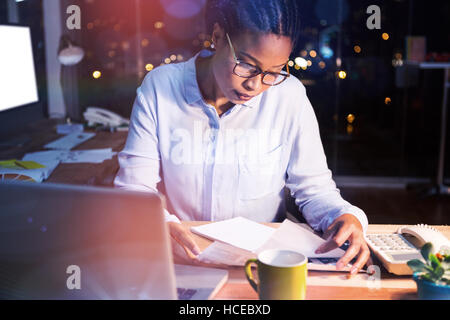 Businesswoman reading document at desk Stock Photo