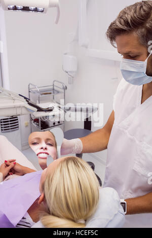 Dentist holding a mirror near patients face Stock Photo