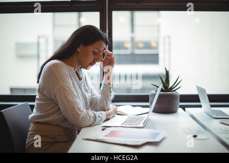 Stressed businesswoman sitting at his desk Stock Photo