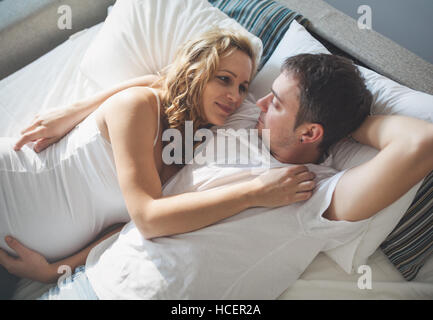 Pregnant happy wife lying in bed with husband Stock Photo