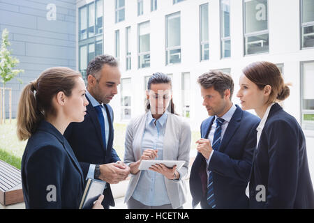 Businesspeople discussing over digital tablet Stock Photo