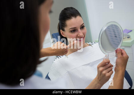 Dentist showing mirror to female patient Stock Photo