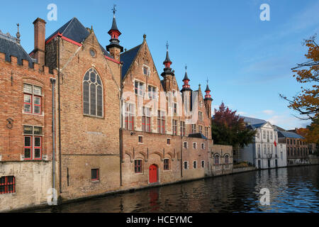 Red brick canal side buildings on the Groenerie canal, . Building on the left is part of the Oude Civiele Griffie (Old County Registry), the  Gothic b Stock Photo