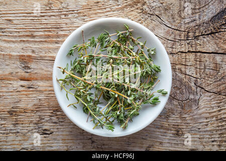 Bowl of thyme on wooden background, top view Stock Photo