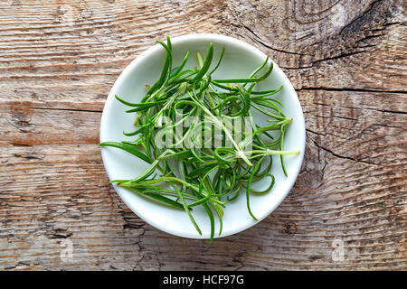 Bowl of rosemary on wooden background, top view Stock Photo