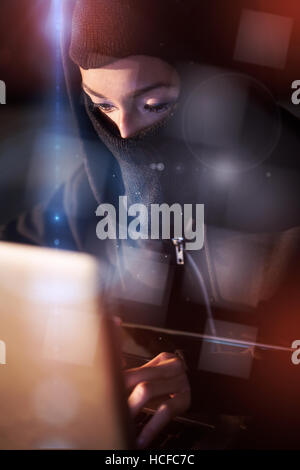 Woman in balaclava using laptop Stock Photo