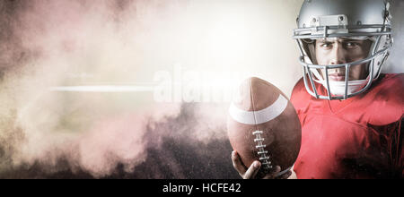 Composite image of portrait of determined american football player with ball Stock Photo