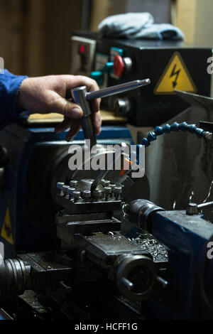 Metalworking. Man working on a small lathe machine in a craftsman workshop. Stock Photo