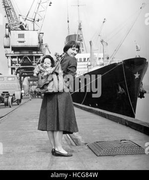 Wearing fur-lined clothes made from his Grandmother's sable evening cloak, four-month-old baby Robin Simpson is attached to his mother via rucksack, prior to departure in the Leda at Newcastle-upon-Tyne, on a journey that is to take them to Spitzbergen for a five-month visit. Robin's mother Myrtle, wife of Dr Hugh Simpson, is going to the Arctic, together with her husband, to take part in an expedition organised to carry out research into the effect of continuous daylight on human beings. Packed amongst the maps, ice picks, instruments and other exploration essentials, are the important Stock Photo