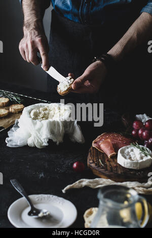 Chef prepares crostini with fresh cheese for a wine dinner or party. Selective focus, desaturated effect, toned image Stock Photo