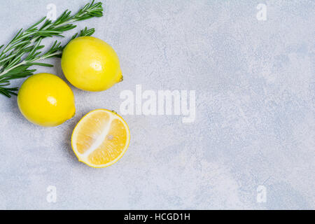 Fresh organic lemons and rosemary on bright blue stone background with copy space for text. Top view. Stock Photo