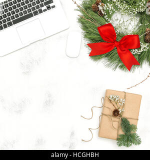 Office desk with laptop, Christmas decoration wreath red ribbon bow and wrapped gift. Top view Flat lay Stock Photo
