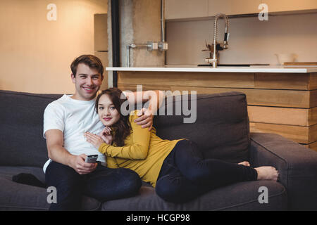 Smiling couple sitting on a sofa watching TV in living room Stock Photo