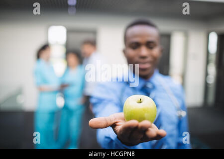 Doctor showing green apple in hospital corridor Stock Photo