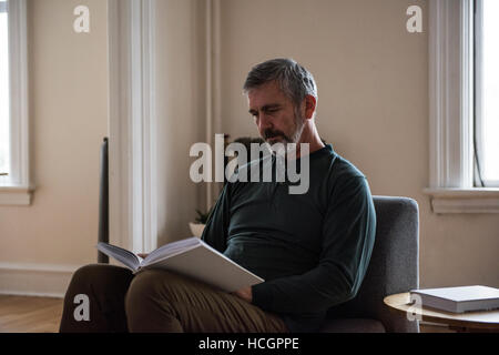 Man reading book in living room Stock Photo