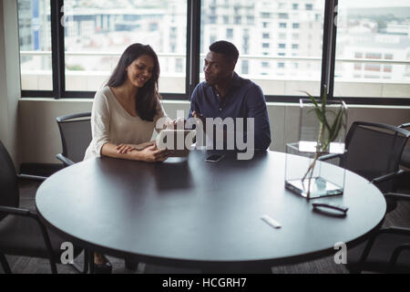 Businessman and a colleague discussing over digital tablet Stock Photo