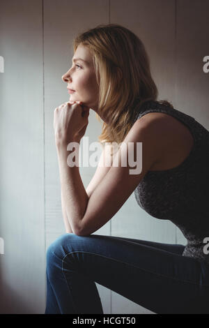 Thoughtful woman sitting with hand on chin Stock Photo