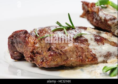 roasted beef steaks with rosemary under white sauce Stock Photo