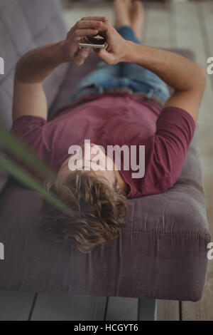 Man lying on sofa and using mobile phone Stock Photo