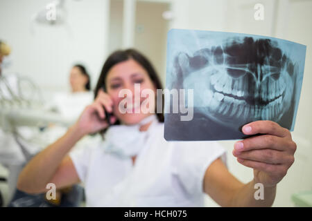 Dentist checking a x-ray report while talking on mobile phone Stock Photo