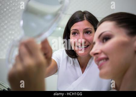 Patient checking her teeth in mirror Stock Photo