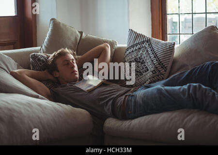 Man sleeping on sofa with a book on chest Stock Photo