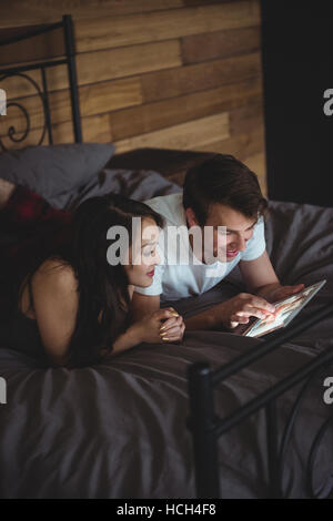 Couple lying on bed using digital tablet in bedroom Stock Photo