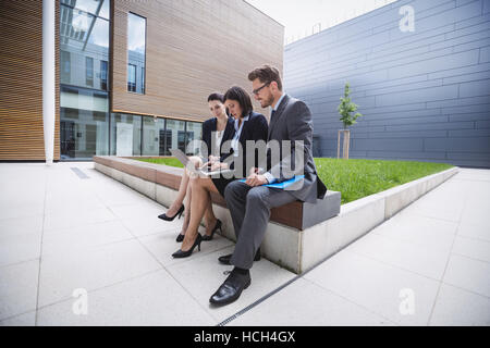 Businesswoman sitting with colleagues and using laptop Stock Photo