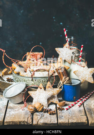 Christmas festive gingerbread cookies or biscuits in vintage tray, decoration rope, nuts, spices, milk for Santa in bottles, sugar powder. Selective f Stock Photo