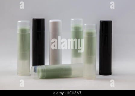 Arrangement of many white, black, and clear chapstick shaped tubes with green content on a white background Stock Photo