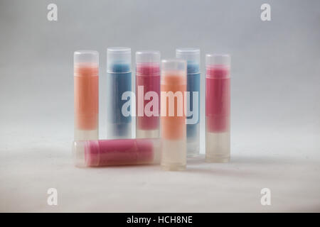 Arrangement of many clear chapstick shaped tubes with orange, blue, and red contents on a white background Stock Photo