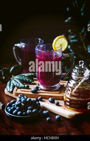 A glass of Blueberry Hot Toddy with lemon garnish is photographed from the front view. Stock Photo