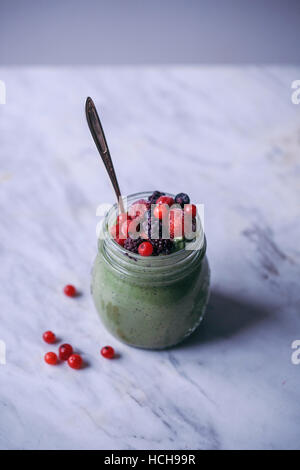 Matcha green tea chia pudding topped with frozen berries in a glass jar Stock Photo