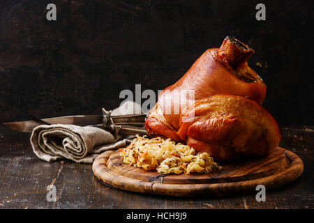 Roasted pork knuckle eisbein with braised boiled cabbage on wooden cutting board Stock Photo