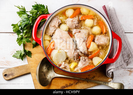 Stewed rabbit with potatoes and carrot in cast iron pot on rustic wooden table background Stock Photo