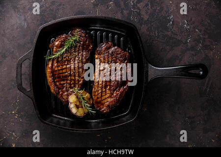 Grilled Black Angus Steak Striploin on frying cast iron Grill pan on dark background Stock Photo