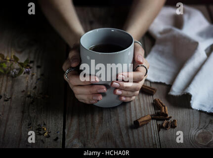 Woman's hands holding a cup of tea on wooden table Stock Photo