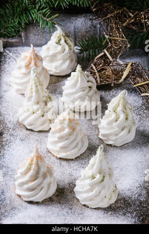 Homemade white french meringue as Christmas fir tree decorated by colored sugar and matcha tee over powdered old metal background with holiday decorat Stock Photo