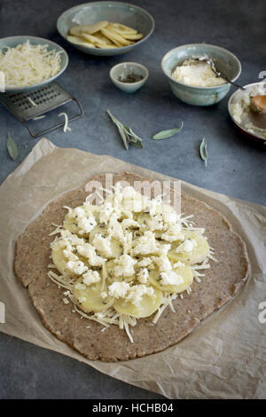Pie dough and ingredients for a potato galette. Photographed on a greay background from top view. Stock Photo