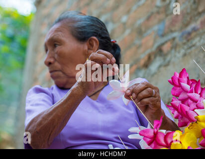 A Salvadoran woman decorates palm fronds with flowers during the Flower & Palm Festival in Panchimalco, El Salvador Stock Photo