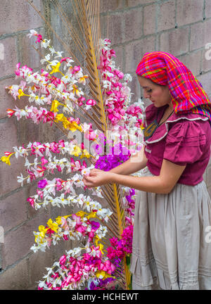 A Salvadoran woman decorates palm fronds with flowers during the Flower & Palm Festival in Panchimalco, El Salvador Stock Photo