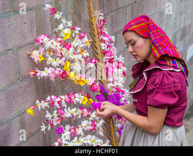 A Salvadoran woman decorates palm fronds with flowers during the Flower & Palm Festival in Panchimalco, El Salvador Stock Photo