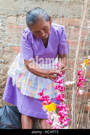 A Salvadoran woman decorates palm fronds with flowers during the Flower & Palm Festival in Panchimalco, El Salvador Stock Photo